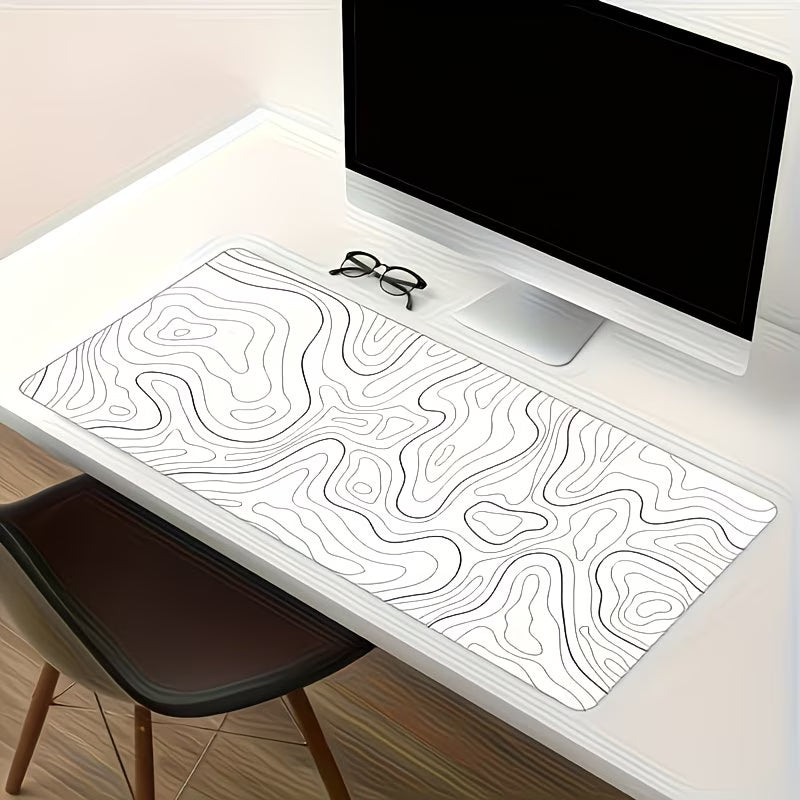 Desk setup with a monitor, glasses, and a large desk mat with wavy line design.